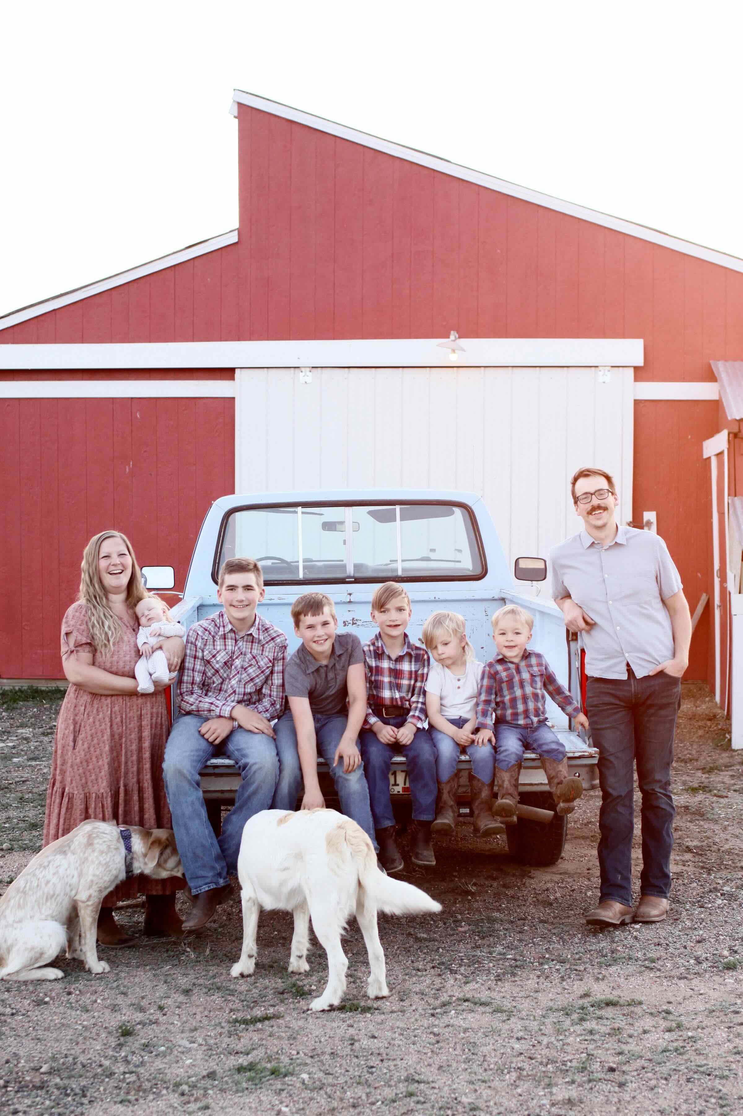 The Szczecina family in front of their red barn with dogs Rosie and Liberty